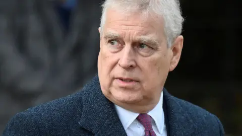  Reuters A man with white hair looks off to the side of the camera. He is wearing a dark blue jacked, a white shirt and a crimson-coloured tie.