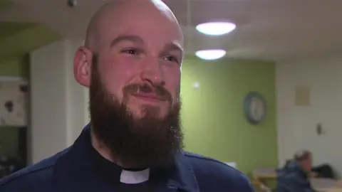 Head and shoulders image of Reverend Matt Lockwood who has a bald head and a long dark brown beard. He is wearing a dog collar and smiling