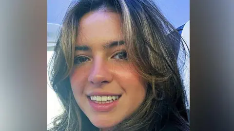 Supplied Girl smiling for the camera with long brown hair.