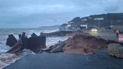 The A379 Slapton Line between Torcross and Slapton has washed away. The image shows a gaping hole in the street.