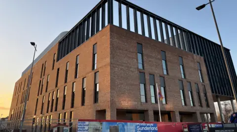 South Tyneside and Sunderland NHS Foundation Trust Sunderland's new eye hospital which is nearly built. The large red brick building has rows of tall, slim windows along its three storeys.