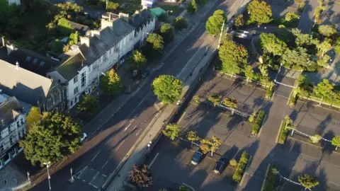 Getty An aerial view of the Queen's Parade area of Bangor, County Down.
A number of buildings can be seen along a straight road opposite a large car park with various trees dotted throughout.