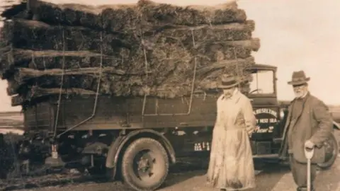 Norfolk Wildlife Trust A black-and-white photograph of Dr Sydney Long and Robert Bishop, Bernard Bishop's great-grandfather. They are standing next to an old lorry laden with what looks like turf.