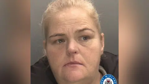 West Midlands Police A mugshot of a lady with blonde hair that is tied back. She is looking to the right of the image and the top of her black coat can be seen. 