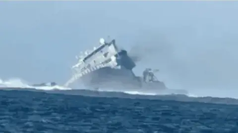 Samoan government HMNZS Manawanui pictured from a distance in the sea appearing to tilt sideways after it crashed in Samoan waters last year.
