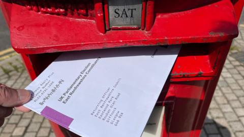 A postal vote being put through a letter box