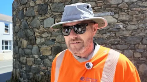 man wearing hat, sunglasses and high visibility clothing.