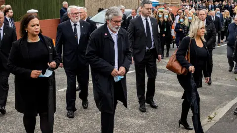 PA Media A group of people walking they are all dressed in black.