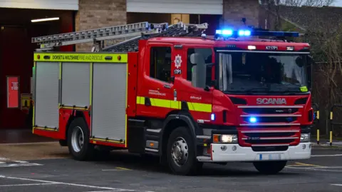 A fire engine with blue lights on at Hamworthy fire station