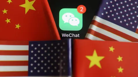 Reuters Messenger app WeChat is seen among U.S. and China flags