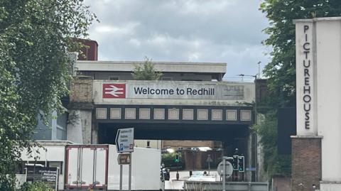 A welcome to Redhill sign on a bridge 