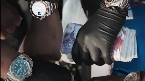 Nottinghamshire Police A closeup showing gloved hands holding bank notes and wearing expensive watches