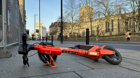 NFBUK A scooter lying on its side in the middle of the pavement