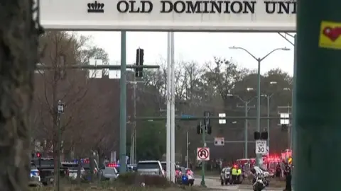 A partialOld Dominion University sign is visible from the street where police vehicles are gathered. 
