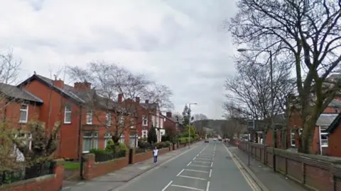 A suburban street with semi-detached houses and a school