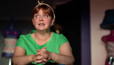 Bernie McCallister Caroline Curran, a woman with fair to brown hair, wearing a hair band and green t-shirt. 
