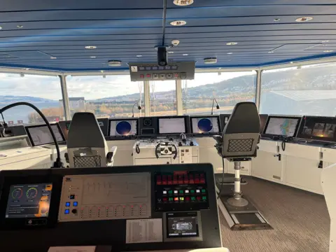 Control panels and two seats, with a "steerin wheel" in the middle. The camera is looking out the front of the bridge of Glen Sannox