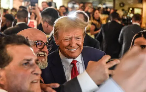 Getty Images Donald Trump poses with patrons during a surprise visit to the Versailles restaurant in Little Havana, Miami, after pleading not guilty in court