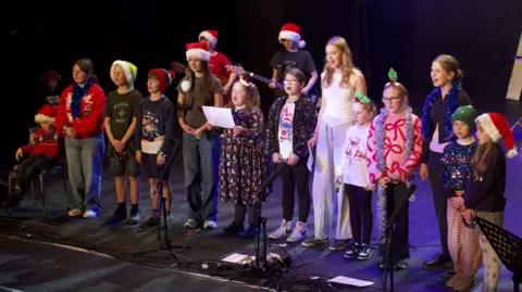 Elusen Hywel Dda Members of the Cân o'r Galon choir on stage singing together on a stage. 