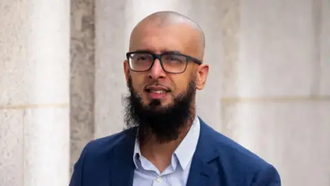 Majid Novsarka has a shaved head and a long beard
