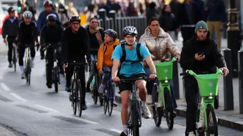 EPA Cyclists ride during rush hour in London. Two lime bike users at the front with more manual bike users to the back.