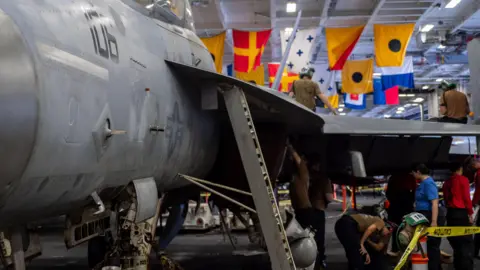 BBC/Natalie Thomas Crews maintaining an F/A18 in the Carl Vinson’s hangar