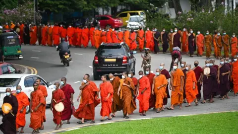 Getty Images Buddhist monks arrive for a meeting at Colombo's Independence Memorial hall in Colombo on April 30, 2022, to express their solidarity with countrymen demonstrating against the government over the country's crippling economic crisis.