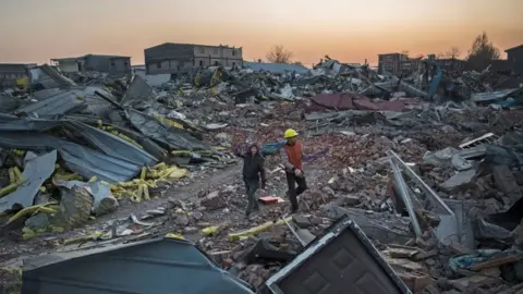 Getty Images Workers salvage material from demolished buildings in Beijing (6 Dec 2017)