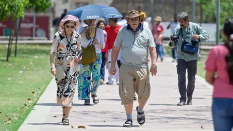 Getty Images Visitors are seen protecting themselves from the sun on a hot summer day outside Humayun's Tomb on April 21, 2026 in New Delhi, India.