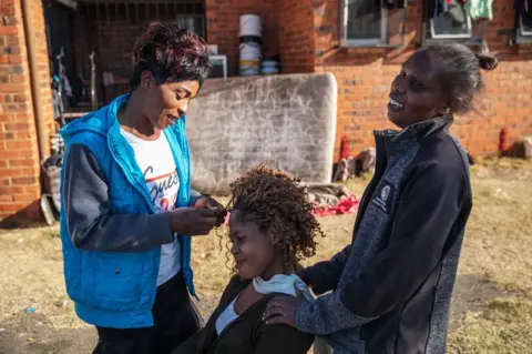 AFP A woman combs another outside the Tsolo Community Hall in Johannesburg"s Katlehong township, on September 9, 2019, where around 250 people, mostly Zimbabwean and Malawian nationals, are hosted after being displaced due to a new wave of anti-foreigner violence that hit South Africa"s financial capital.