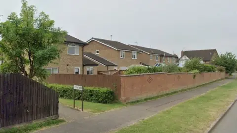 Modern houses behind a brick wall. A footpath to the left is signed "Lovap Way"