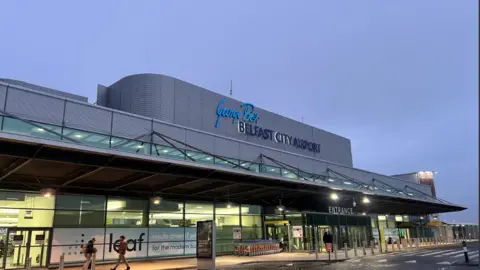 The front of Belfast City Airport near the entrance, with people walking outside