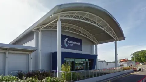 Google The entrance to the Bournemouth Airport terminal, a grey building with a curved roof.