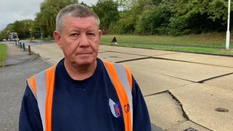 Stuart Woodward / BBC Charlie Mann, warehouse manager at Alpi UK Basildon, standing next to the damaged section of Miles Gray Road