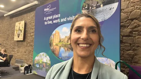 A woman with long dark hair smiles at the camera