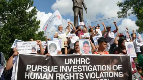 Getty Images Relatives of victims of extrajudicial killings hold portraits of their relatives during a memorial mass at the Philippine Human Rights Commission on July 9, 2019