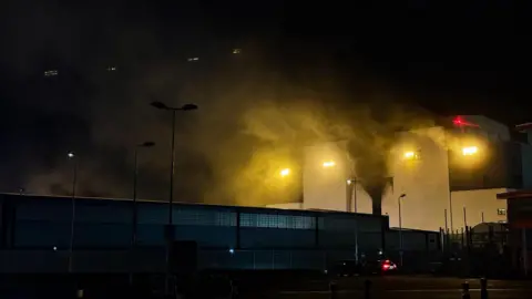 Smoke coming from the white building at night-time.