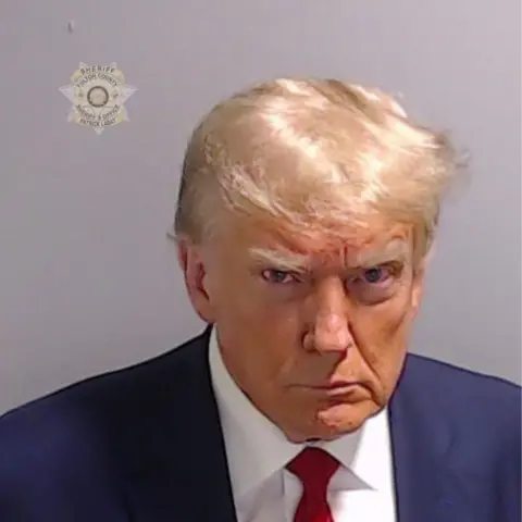 Handout/Getty Images Donald Trump, in navy blazer and red tie, poses for his booking photo at the Fulton County Jail on 24 August, 2023, in Atlanta, Georgia. 