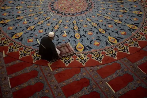EPA A man kneels in prayer inside a mosque.
