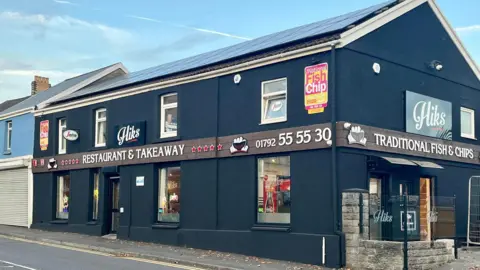 Leanne Jones A two-storey building which is painted dark blue with a 'Hiks Restuarant and Takeaway' sign