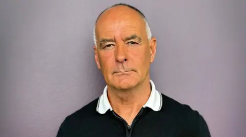 Tommy Sherdian head and shoulder shot in a black top with white collar