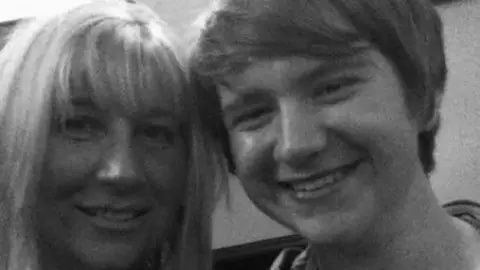 Alex Cottam in a black-and-white photograph alongside his mum Michelle Cottam. Both are smiling.