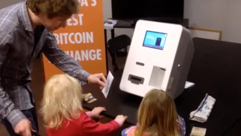 Courtesy Alex Salkeld Gerald Cotten in 2014 showing Alex Salkeld's daughters how to use a Bitcoin automatic teller