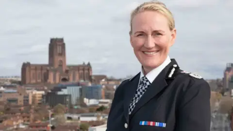 Chief Constable Serena Kennedy wears black police uniform, her blonde hair is pulled back from her face and she smiles at the camera. 