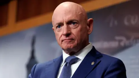 EPA US Senator Mark Kelly, wearing a blue suit and blue tie, looks straight ahead 