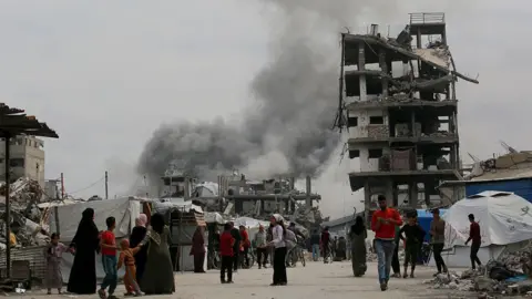 AFP Palestinians take cover as an Israeli strike hits a home in Jabalia, in the northern Gaza Strip (15 May 2025)