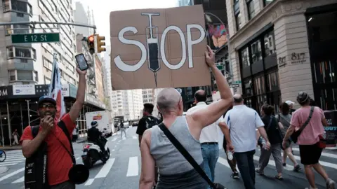 Getty Images woman at protest holding stop vaccines sign
