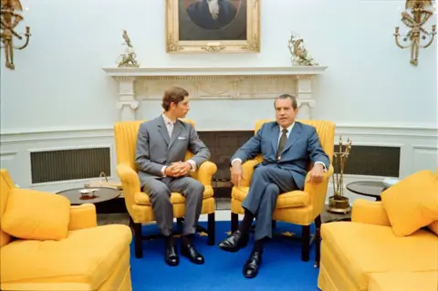 Getty Images In 1970, Charles was 21 years old when he sat in the White House Oval Office with President Richard Nixon. The two sit in yellow cushioned chairs, with blue carpet below.