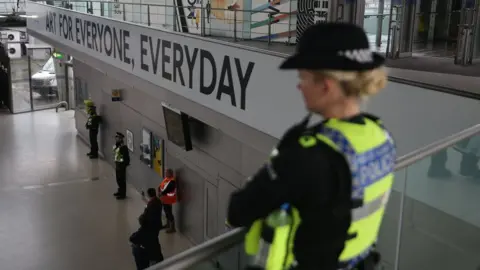 Getty Images Police officers pause for a minutes' silence at Stratford station in London