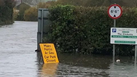 Closed sign floating in flood water in car park